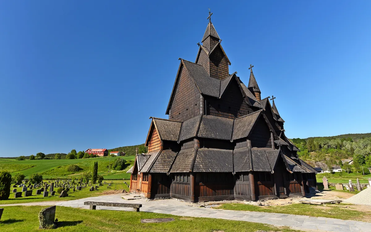Holzkirche im Grünen, blauer Himmel, Friedhof im Vordergrund