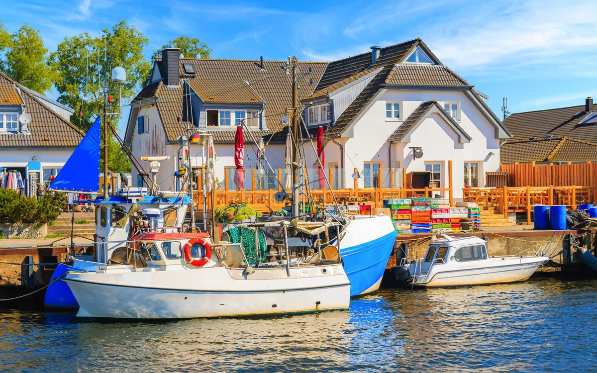 Boote am Kai vor einem Haus mit Sonnenschirmen und Deko im Freien.