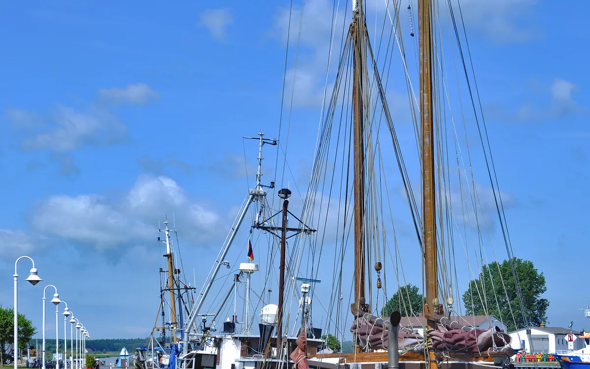 Segelschiffe im Hafen bei blauem Himmel und Wolken.