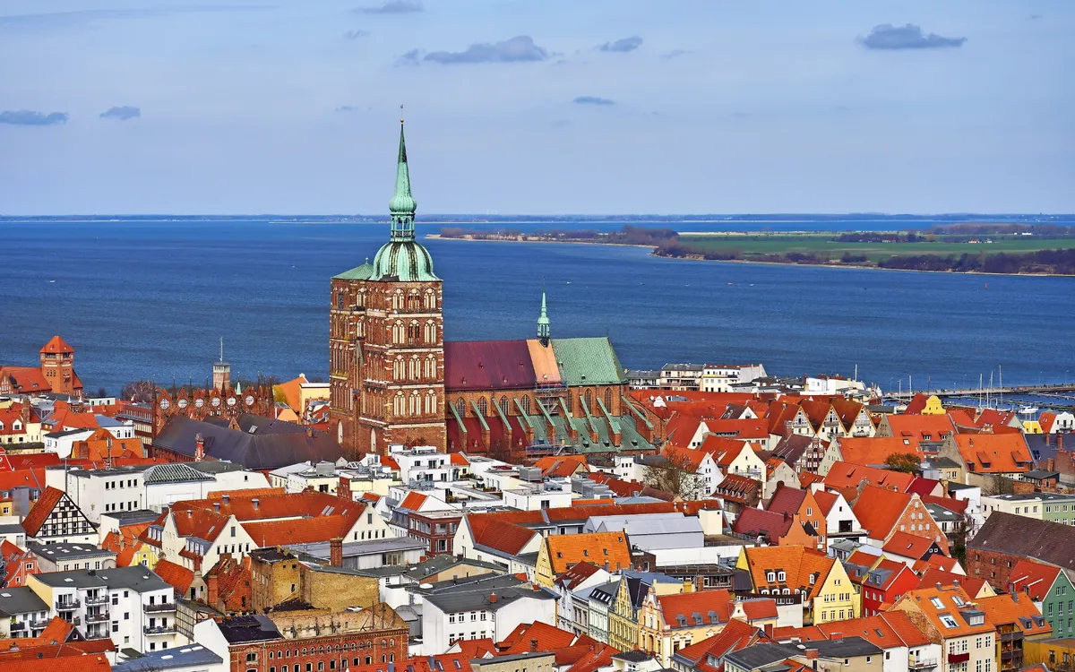 Stadtansicht mit historischem Kirchturm und Blick aufs Meer.