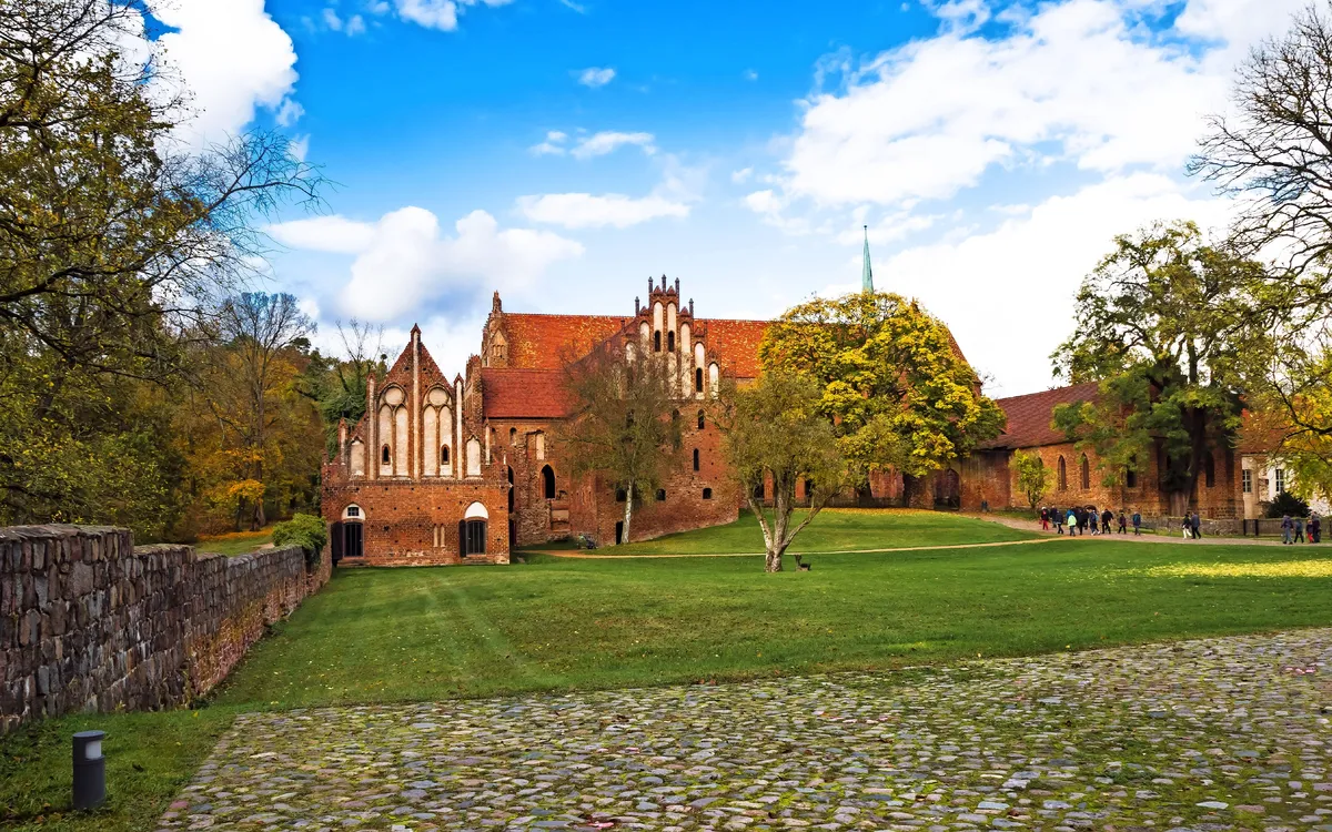 Historische Backsteinarchitektur mit Rasen und Bäumen im Vordergrund.