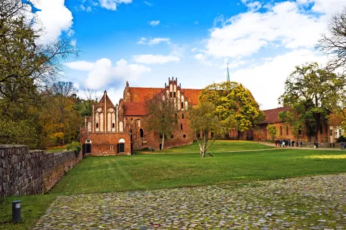 Historische Backsteinarchitektur mit Rasen und Bäumen im Vordergrund.