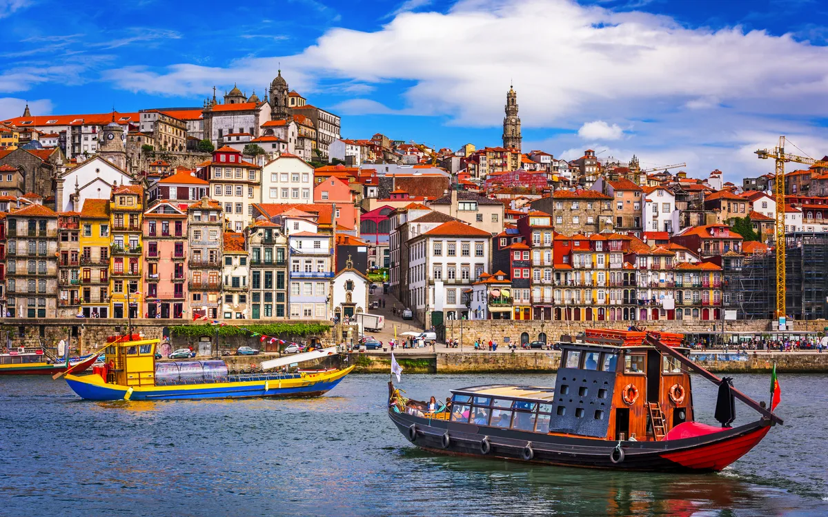 Boote auf dem Fluss vor der bunten Skyline von Porto, Portugal.