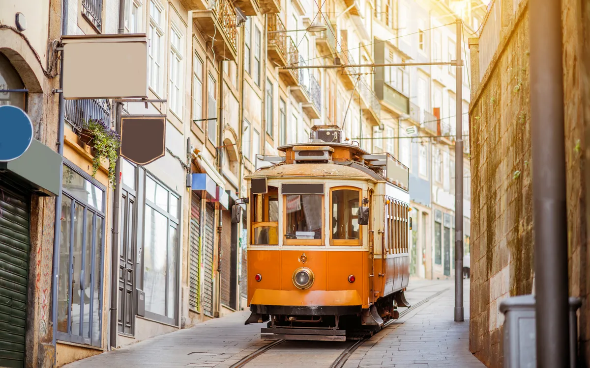 Straßenbahn fährt durch enge Altstadtgasse mit historischen Gebäuden.