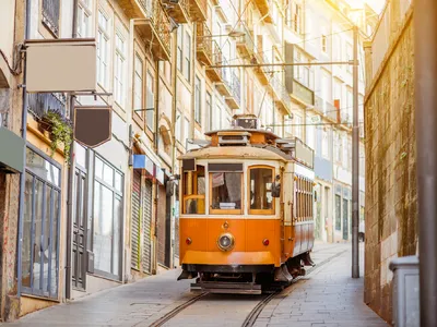 Straßenbahn fährt durch enge Altstadtgasse mit historischen Gebäuden.