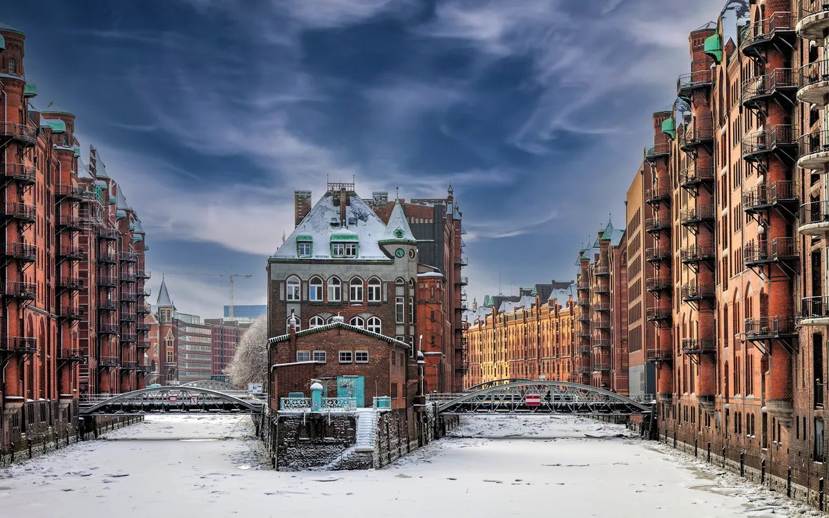 Backsteinbauten im Winter in Hamburg mit schneebedecktem Kanal.
