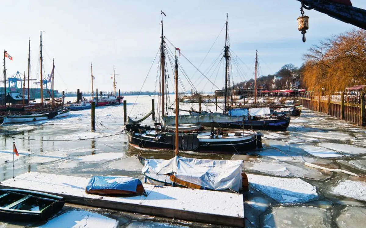 Segelboote im teilweise zugefrorenen Hafen von Hamburg im Winter unter klarem Himmel.
