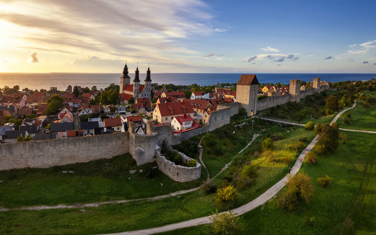 Drohnenaufnahme von Visby mit Stadtmauer und Kathedrale bei Sonnenuntergang.