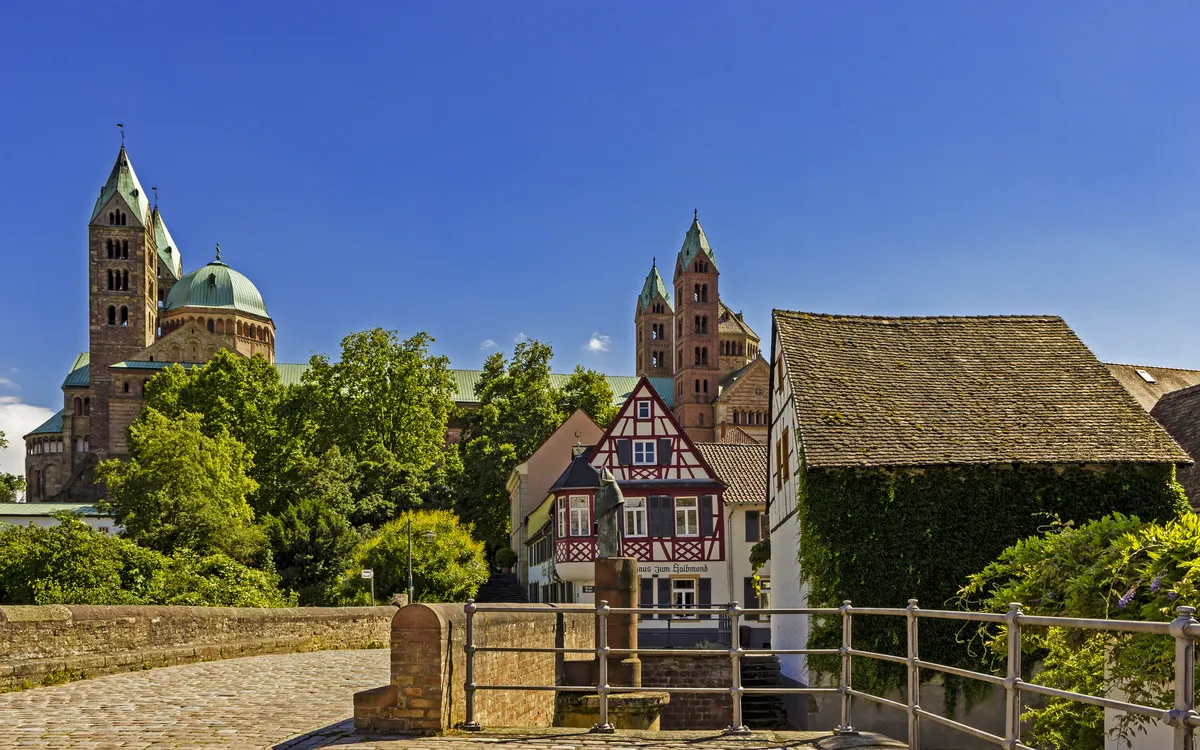 Dom zu Speyer mit Fachwerkhäusern im Vordergrund an einem sonnigen Tag.
