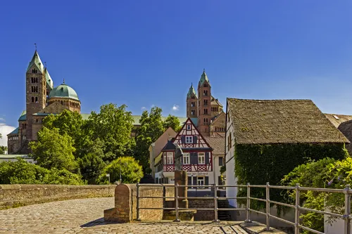 Dom zu Speyer mit Fachwerkhäusern im Vordergrund an einem sonnigen Tag.