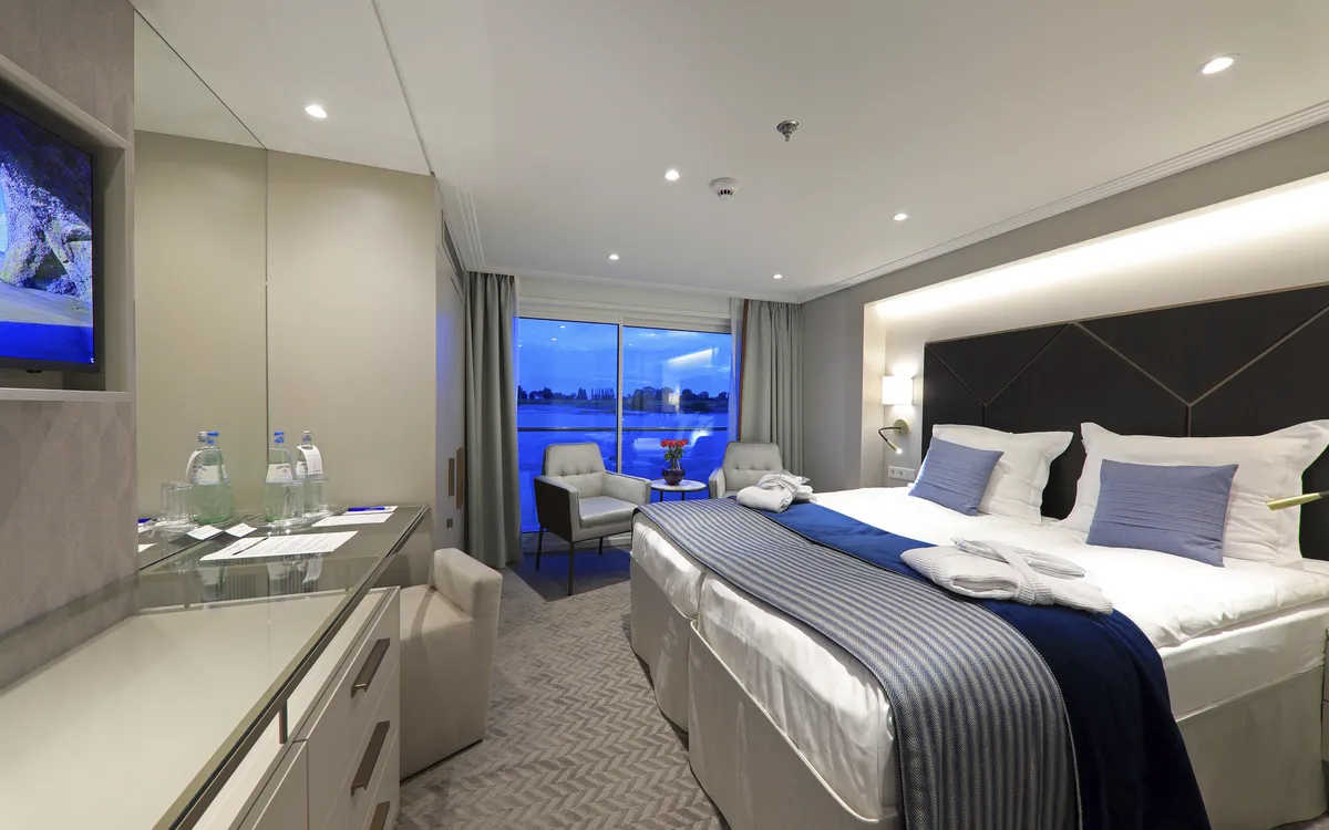 Moderne Kabine auf der MS Lady Diletta mit Doppelbett und Ausblick auf das Wasser.