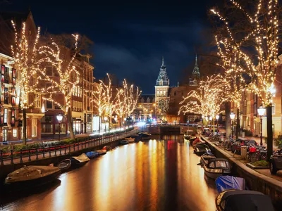 Amsterdam im Winter mit beleuchteten Bäumen am Kanal und Rijksmuseum im Hintergrund.