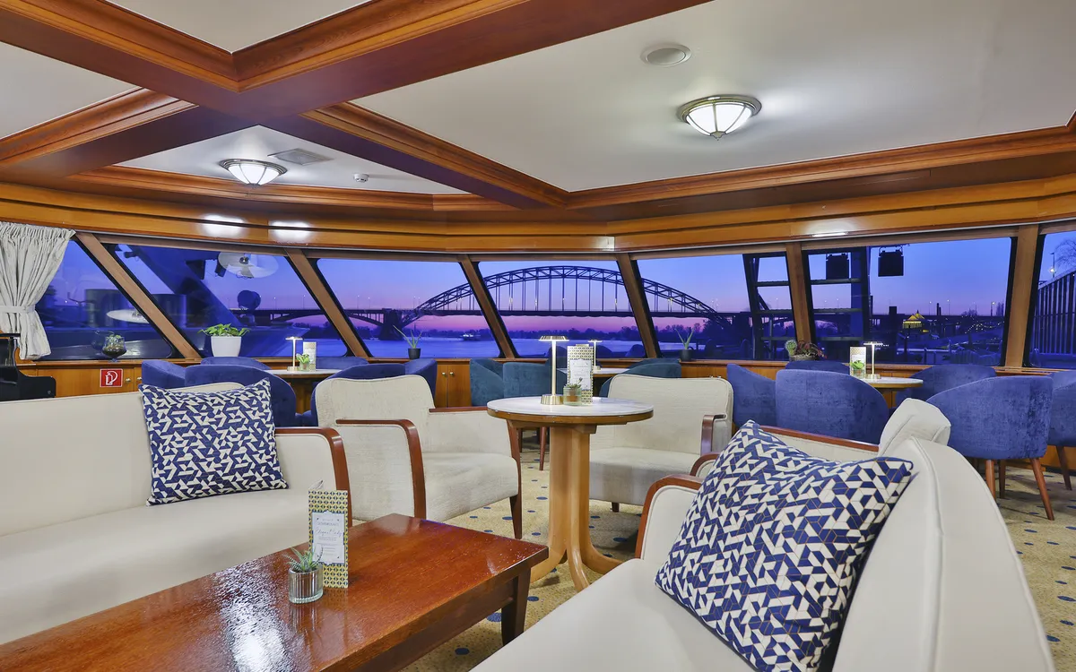 Elegante Lounge mit weißen Sofas und Holztischen auf dem Kreuzfahrtschiff MS Elegant Lady.