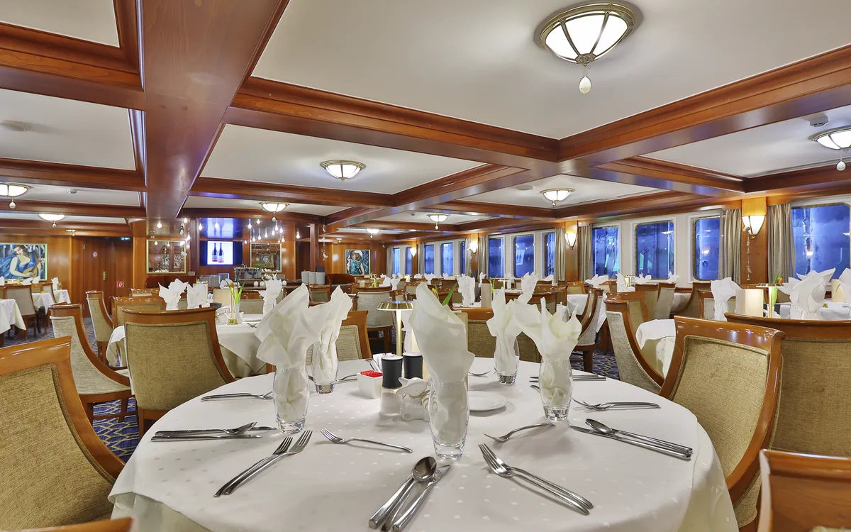 Elegant eingerichtetes Restaurant mit gedeckten Tischen auf einem Schiff.