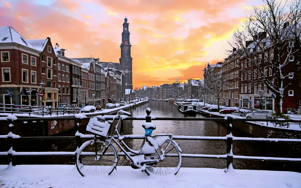 Winterliches Stadtbild von Amsterdam mit der Westerkerk und verschneitem Kanal.