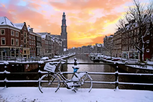 Winterliches Stadtbild von Amsterdam mit der Westerkerk und verschneitem Kanal.