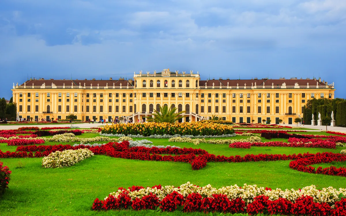 Barockschloss mit aufwendig gestalteten Blumenbeeten im Vordergrund.