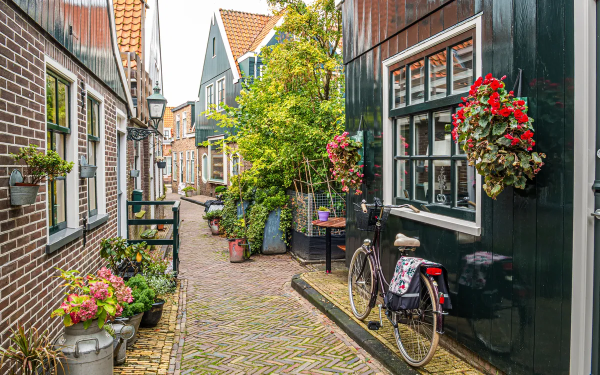 Fahrrad an einer blumengeschmückten Hausfassade in der Straße Kerkepad in Volendam.