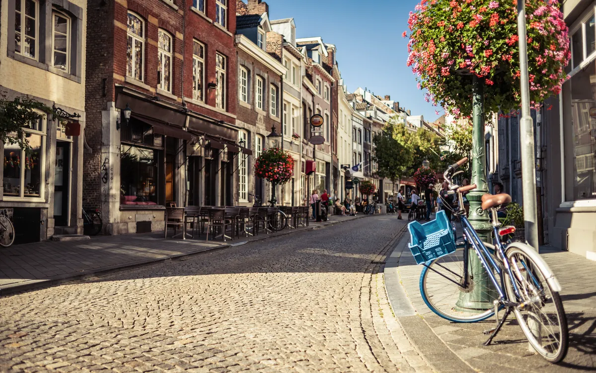 Gepflasterte Maastrichter Straße mit geparktem Fahrrad im Sommer.