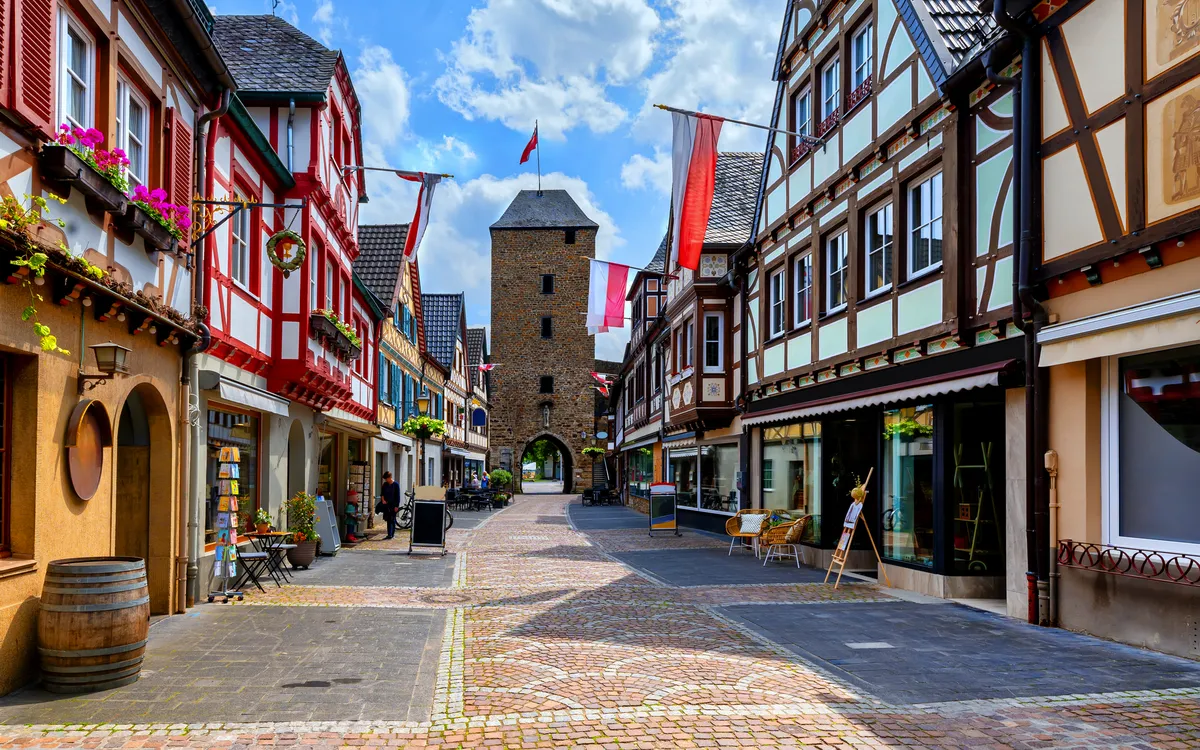 Blick auf eine historische gepflasterte Altstadtstraße mit Fachwerkhäusern.