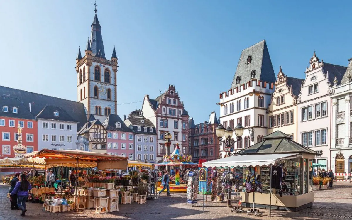 Marktplatz mit historischen Gebäuden, Verkaufsständen und blauem Himmel.