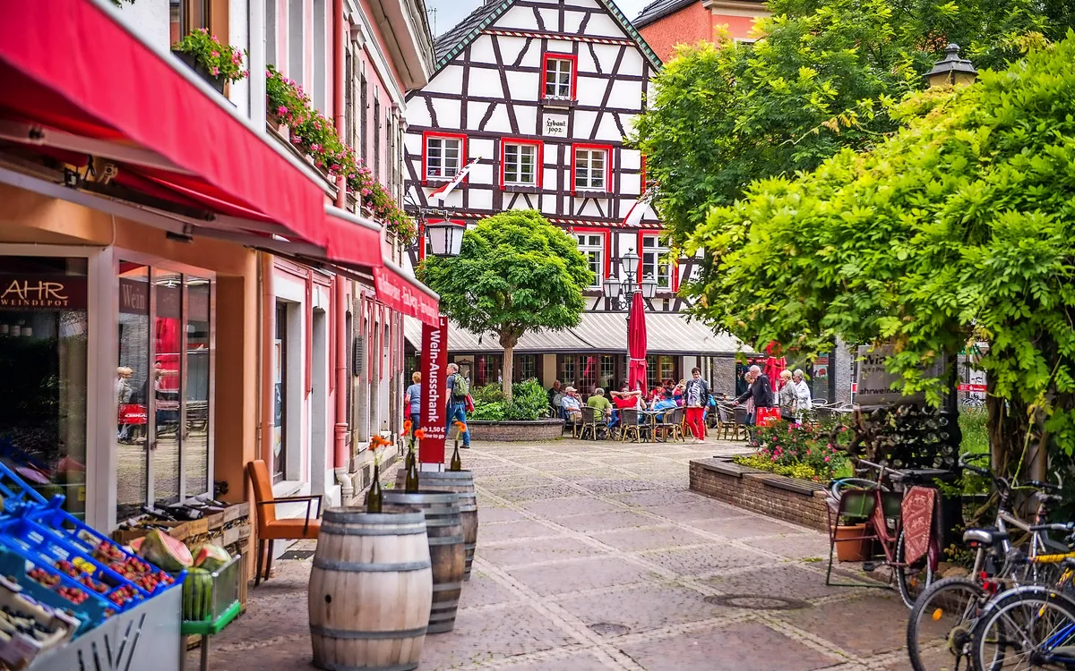 Fachwerkhäuser und Cafés am Marktplatz in Ahrweiler mit Besuchern.