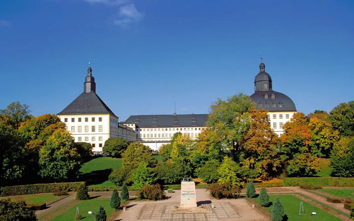 Schloss Friedenstein in Gotha, umgeben von Bäumen und Parkanlagen.